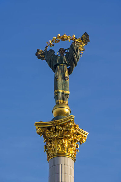 Independence Monument with high white marble column and bronze statue with golden decorations on it. Khreschatyk Street in Kiev, Ukraine, near The Founders of Kyiv Monument