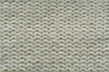 Örülmüş doku. Yünden desenli kumaş. Arka plan, kopyalama alanı. El yapımı süveter dokusu, yün örgü deseni, fildişi arkaplan