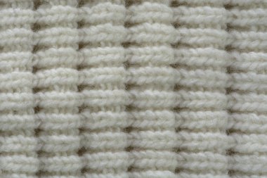 Örülmüş doku. Yünden desenli kumaş. Arka plan, kopyalama alanı. El yapımı süveter dokusu, yün örgü deseni, fildişi arkaplan