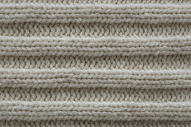Örülmüş doku. Yünden desenli kumaş. Arka plan, kopyalama alanı. El yapımı süveter dokusu, yün örgü deseni, fildişi arkaplan