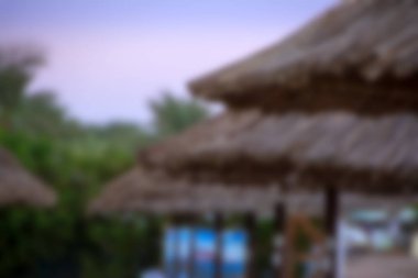 Hasır şemsiyeler ile gün batımında tropikal plaj soyut bulanık bakış. Tatil ve Turizm kavramı