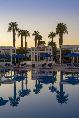 Sharm El-Sheikh, Qesm Sharm kül Sheikh, Mısır - 28 Ekim 2018: Mısır Maritim Jolie Ville Resort Tatil. İnsanlar akşam havuz bir dinlenme var. Palmiye ağaçları havuzu sakin suda yansıtılır