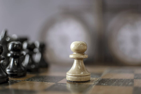 Старая шахматная доска с фигурами и винтажными шахматными часами на размытом фоне. Красивый концептуальный фон для дизайна и текста с мягким светом. Селективный фокус
