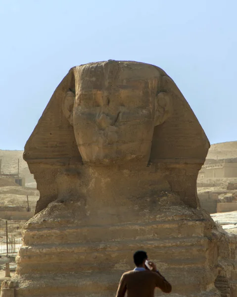 Blurred silhouette of the tourist talking by smartphone against The Great Sphinx of Giza on background, Cairo in Egypt. Conceptual scene showing the contrast of the past and nowadays