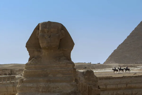 埃及吉萨开罗蓝天上的凯芬狮身人面像和金字塔 贝都因人和游客在背景中骑着马和骆驼 — 图库照片