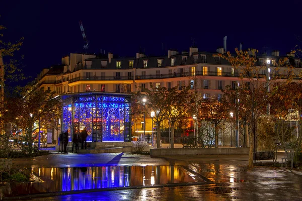 フランスで雨の後に水に反映された美しい照明付きの建物と青いパビリオンを持つカラフルな夜の都市のシーン — ストック写真