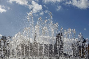 Notre Dame de Paris bulanık silueti ile mavi bulutlu gökyüzüne karşı çeşme yakın çekim sıçrama suyu, Fransa