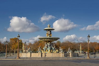 Fontaine Place de la Concorde (Fontaine des Mers) arka plan Paris, Fransa üzerinde sonbahar ağaçları ile mavi bulutlu gökyüzü altında
