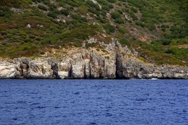 Yunanistan'ın Othonoi gizemli adasındaki kayalardaki mağaralar. Ada ve lacivert deniz ile kontrast güzel sahne