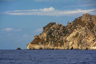 Yunanistan'ın Othonoi gizemli adasındaki kayalardaki mağaralar. Lacivert deniz ve mavi gökyüzü arasında ada ile kontrast güzel sahne