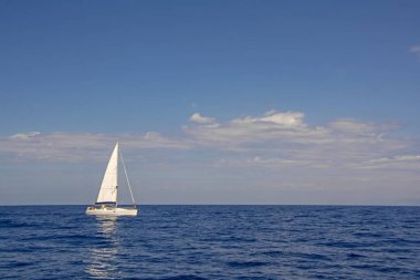 Dalgalar üzerinde yansıması ile mavi denizde güzel lüks beyaz yelkeny. Seyahat, macera ve tatil kavramı