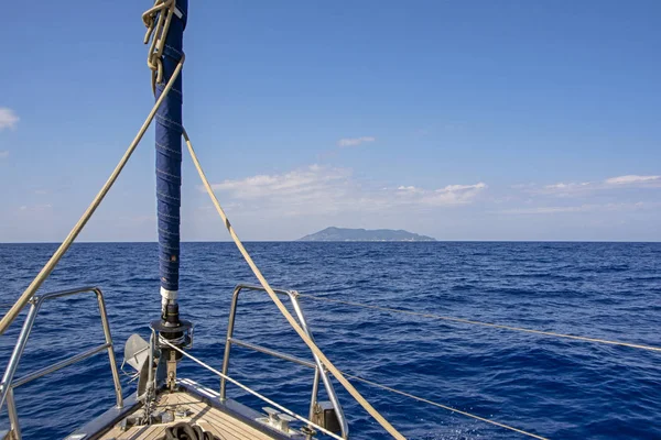ネイビーブルーの深海 背景に神秘的な島 前景に豪華な帆ヨットの木製のデッキと美しいシーン 休暇の概念 — ストック写真