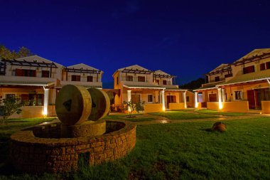 Erikousa adasında sakin bir akşam, Güzel ışıklı evler ve yeşil çim mavi yıldızlı gökyüzü altında taş iyi ve antik değirmen taşları ile dekore ile Yunanistan