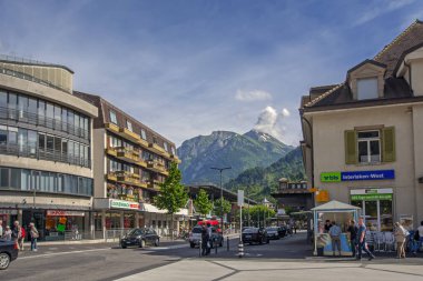 Interlaken, İsviçre - 14 Haziran 2015: İsviçre'de güneşli bir gün arka planda Alpler ve mavi gökyüzü ile insanlar ve trafik dolu