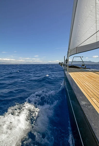 ネイビーブルーの深海 背景に神秘的な島と前景に白い帆と豪華な帆ヨットの木製のデッキと美しいシーン 休暇の概念 — ストック写真