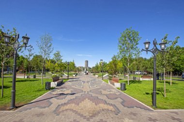 Ermeni halı deseni, yeşil ağaçlar, metal sokak lambaları ve mavi gökyüzü ile mozaik zemin çalışmaları ile şehir parkı perspektif güzel görünümü Erivan, Ermenistan arka planda