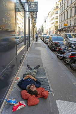 Paris, Fransa - 14 Kasım 2018: Park halindeki araçların yakınındaki kaldırımda uyuyan evsiz dilenciile dikey perspektif sahnesi