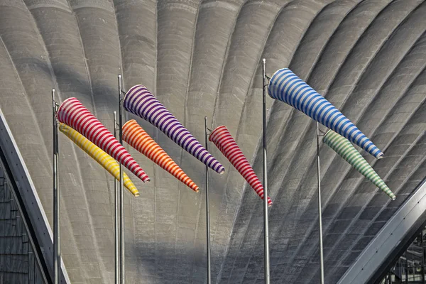 Striped varicoloured windsocks on building wall background in windy weather indicate the local wind direction also called: air sock, drogue, wind sleeve, wind cone