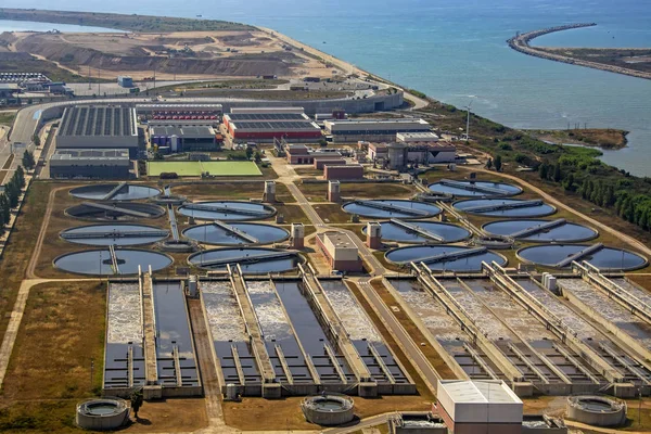 Aerial view of water cleaning factory with blue sea background. Sewage treatment purification industry watering pipe systems and processes. Purity and storage purification, recycled industrial water