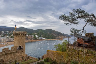 Antik top ve Castell de Tossa de Mar costa Brava üzerinde eski şehir Tossa de Mar ortaçağ kale, Katalonya, Arka planda mavi deniz ile dramatik bulutlu gökyüzü altında İspanya