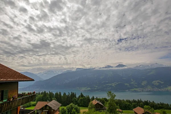 位于瑞士贝登堡白云下的瑞士阿尔卑斯山森林覆盖山区斜坡上的茅屋和图恩湖 — 免费的图库照片
