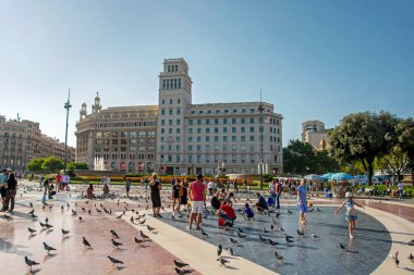 Barselona, İspanya - 31 Temmuz 2019: Katalonya Meydanı 'ndaki insanlar ve güvercinler (Placa de Catalunya) şehrin merkezi olan güneş ışığıyla aydınlatıldı