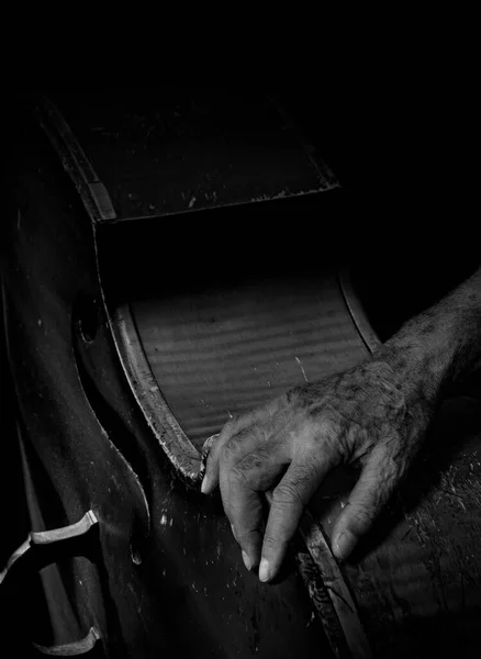 Abstract minimalist conceptual scene with old musician\'s hand on vintage scratched contrabass against black background. Serious music, sadness and loneliness concept. Black and white photography