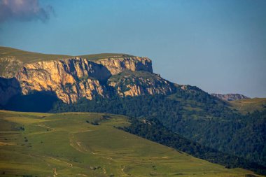 Gün batımında aydınlanan dağ yamacı bulutlu mavi gökyüzü, Dilijan, Ermenistan