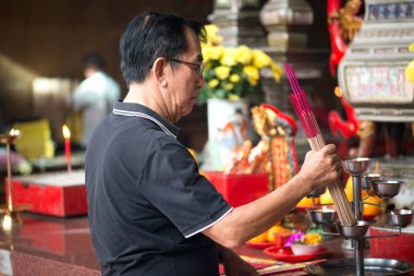 Penang, Malezya Ocak 2015 Malezyalı adam Penang, Malezya, Georgetown 'daki Kek Lok Si tapınağında tütsü çubukları yakıyor.