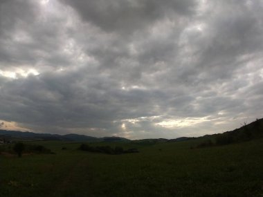 Yeşil ağaçlı ve fırtınalı gökyüzü