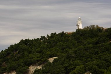 Ormanlık bir tepenin üstündeki deniz feneri.