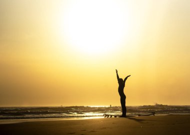 Gün batımında sahilde egzersiz sörfçü silueti