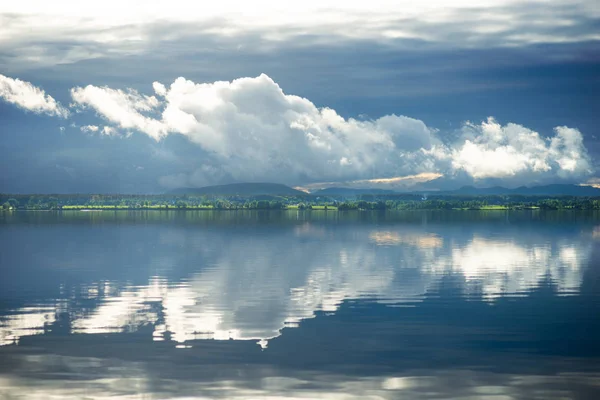 Cloudy blue sky with sunshine refleced in lake