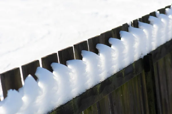 阳光透过雪在木栅栏上闪耀 — 图库照片