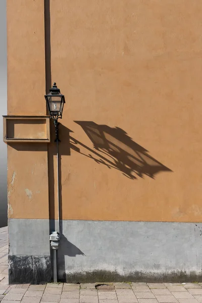 コンクリートの壁に影を落とす街角の昔ながらのランプポスト — ストック写真