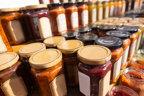 glass jars of jam or marmalade on shelf on outdoor farmers market