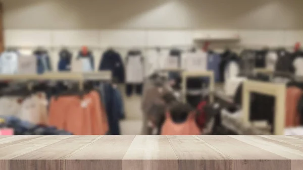 Boş ahşap masa ve bulanık giyim mağazası