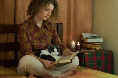 Kız ve yatakta açık bir kitap okuma bir kedi