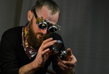 Steampunk adamı gözlük takıyor ve robotu elinde tutuyor