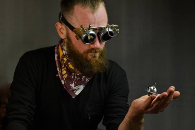 Steampunk adamı gözlük takıyor ve robotu elinde tutuyor