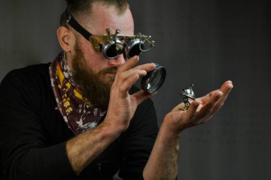 Steampunk adamı gözlük takıyor ve robotu elinde tutuyor