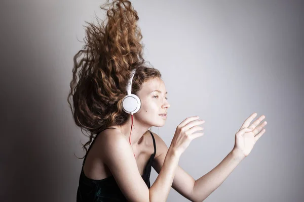 Красива Молода Жінка Слухає Музику Навушниками Перед Білою Стіною — стокове фото