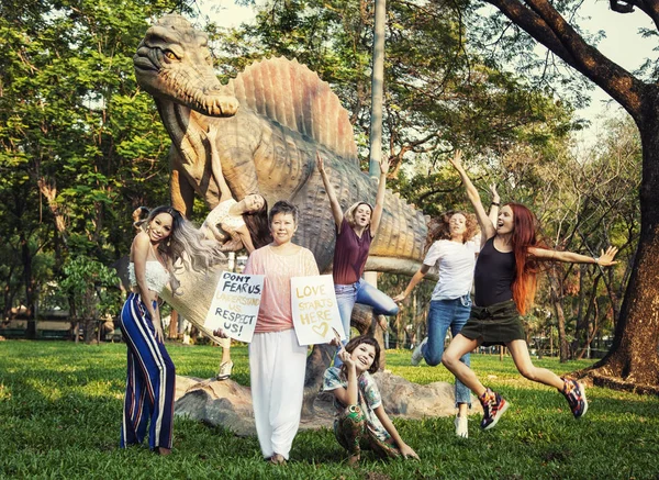 Asian woman in the park next to a dinosaur with a poster 