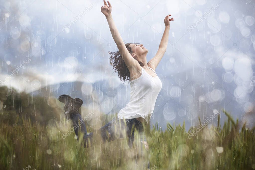 Joyful blonde girl enjoys her evening in the countryside by dancing in the rain