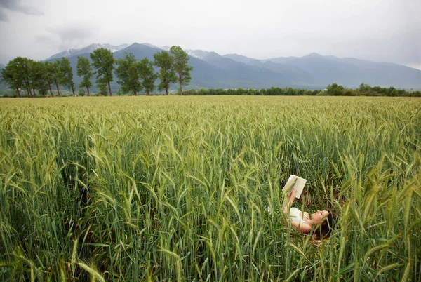 girl lies in the field and reads a book