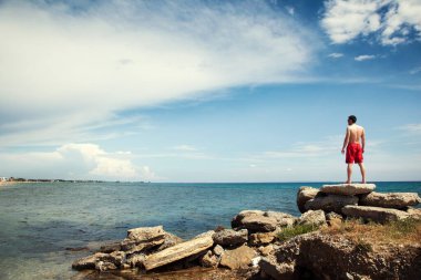 Kumsalda ve denizde genç bir adam