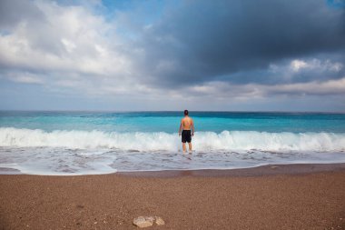 Kumsalda ve denizde genç bir adam