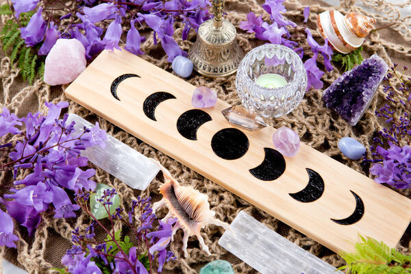 Witch Pagan Moon Phases Altar with crystals of selenite and amethyst, with candle and purple flowers