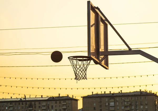 Мяч летит в баскетбольную сетку на закате — стоковое фото