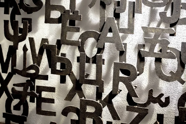 Metal letters attached to a wall form an artistic pattern